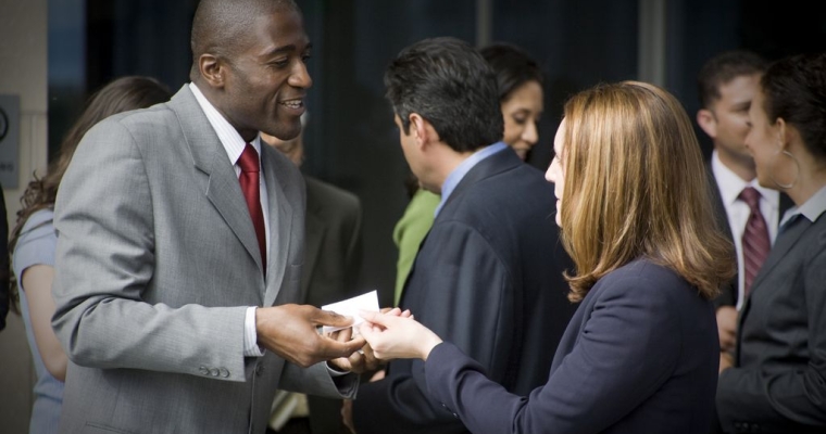 Man and woman in suits shaking hands at event